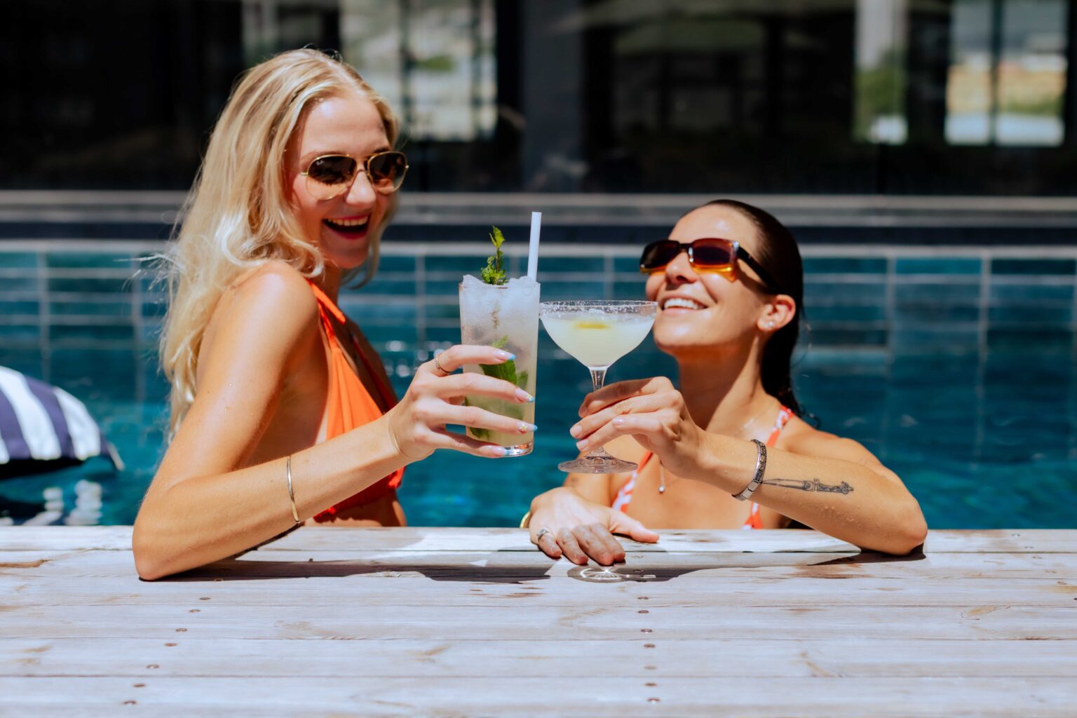 Two guests with cocktails at the edge of the rooftop pool