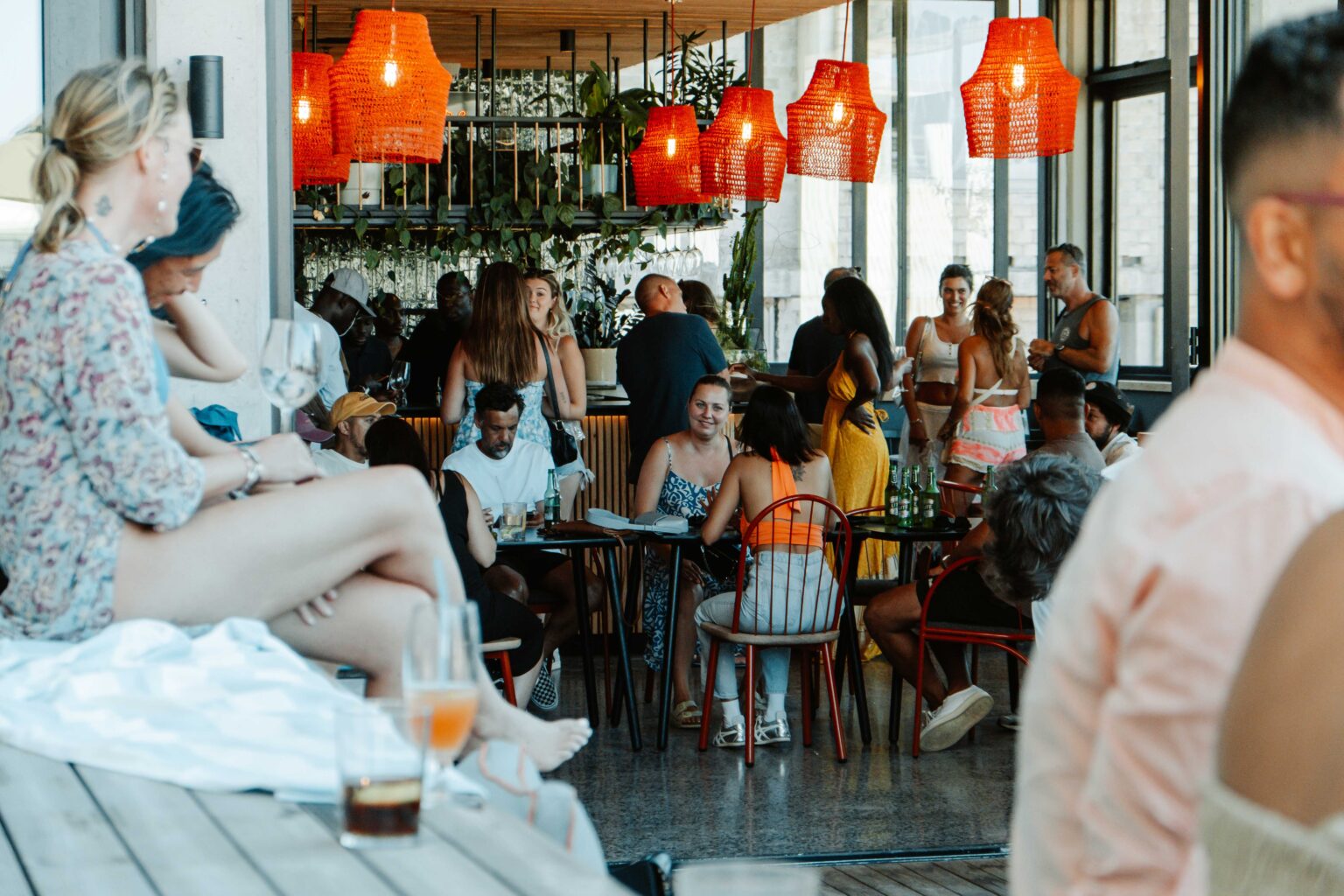 Guests filling the Somewhere Nowhere bar beneath red woven pendant lights